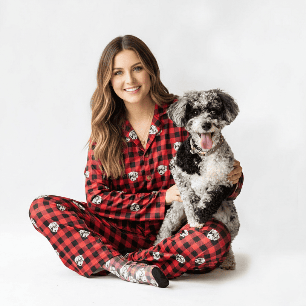 A woman in red doggie pajamas holds a small, fluffy white dog in her arms.